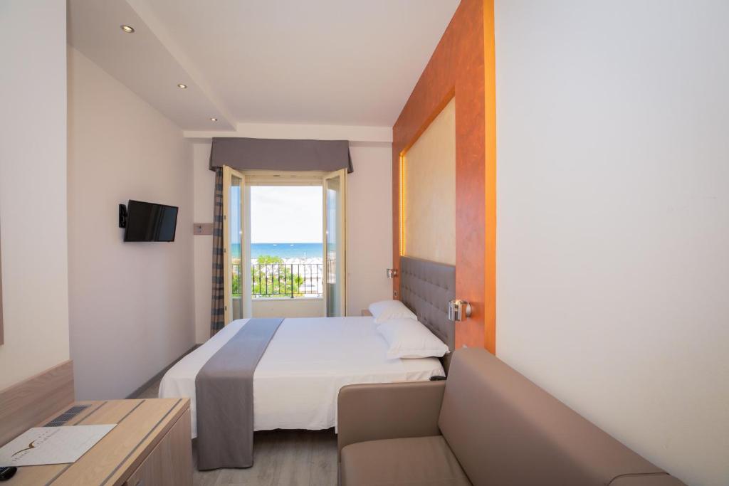 a bedroom with a bed and a couch and a window at Hotel Gabbiano in Rimini