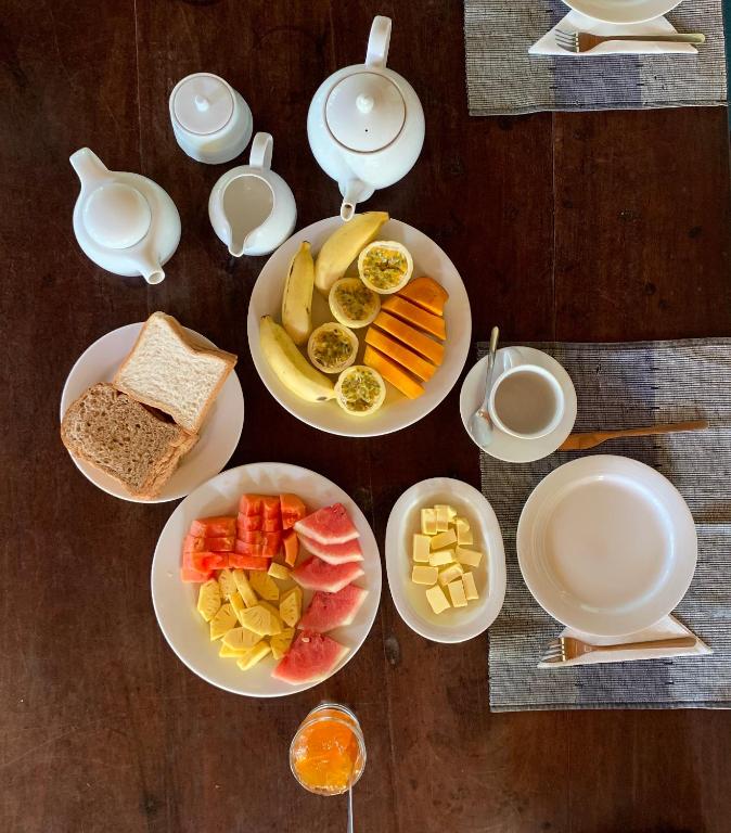 a table with plates of food and bowls of fruit at Green Escape Unawatuna in Unawatuna
