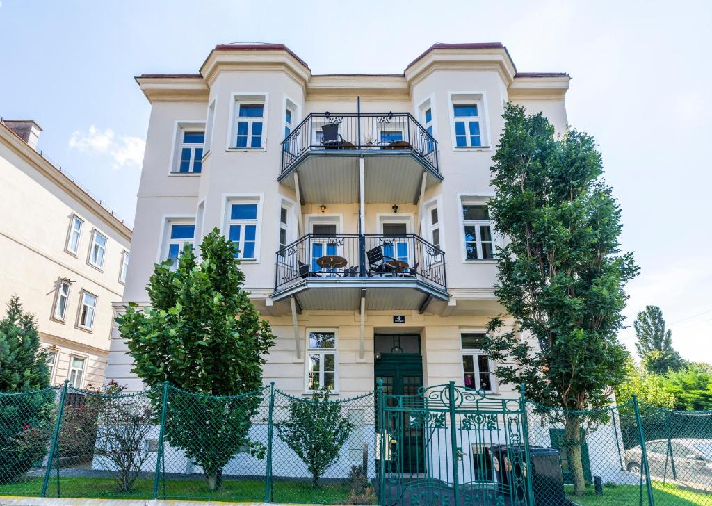 a white building with a fence in front of it at Imperial Apartments Schönbrunn - Contactless Check-In in Vienna