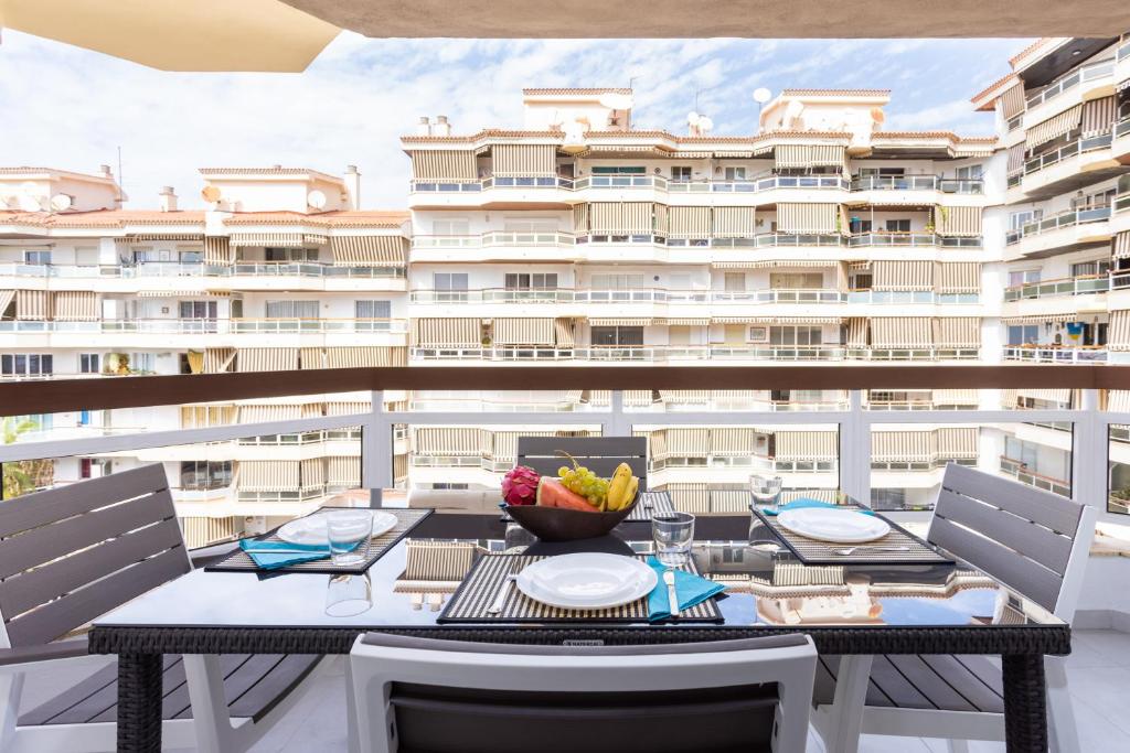 un balcón con mesa y sillas y un gran edificio en Home2Book Paradise Los Cristianos, Pool & Wifi, en Arona