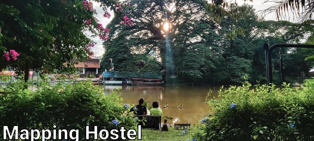 deux personnes assises sur un banc devant une masse d'eau dans l'établissement Mapping Hostel, à Chiang Mai