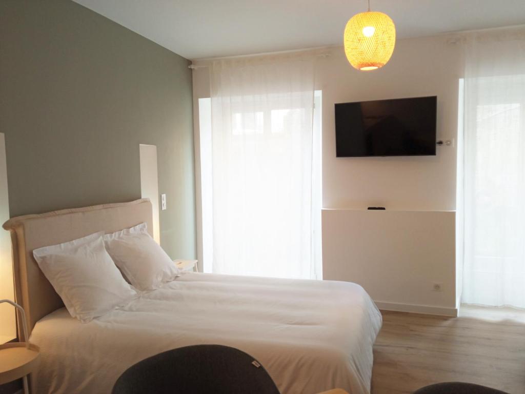 Schlafzimmer mit einem weißen Bett und einem TV an der Wand in der Unterkunft Résidence Oceanica in Bourbonne-les-Bains