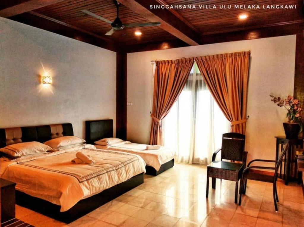 sypialnia z 2 łóżkami i dużym oknem w obiekcie Singgahsana Villa w mieście Pantai Cenang