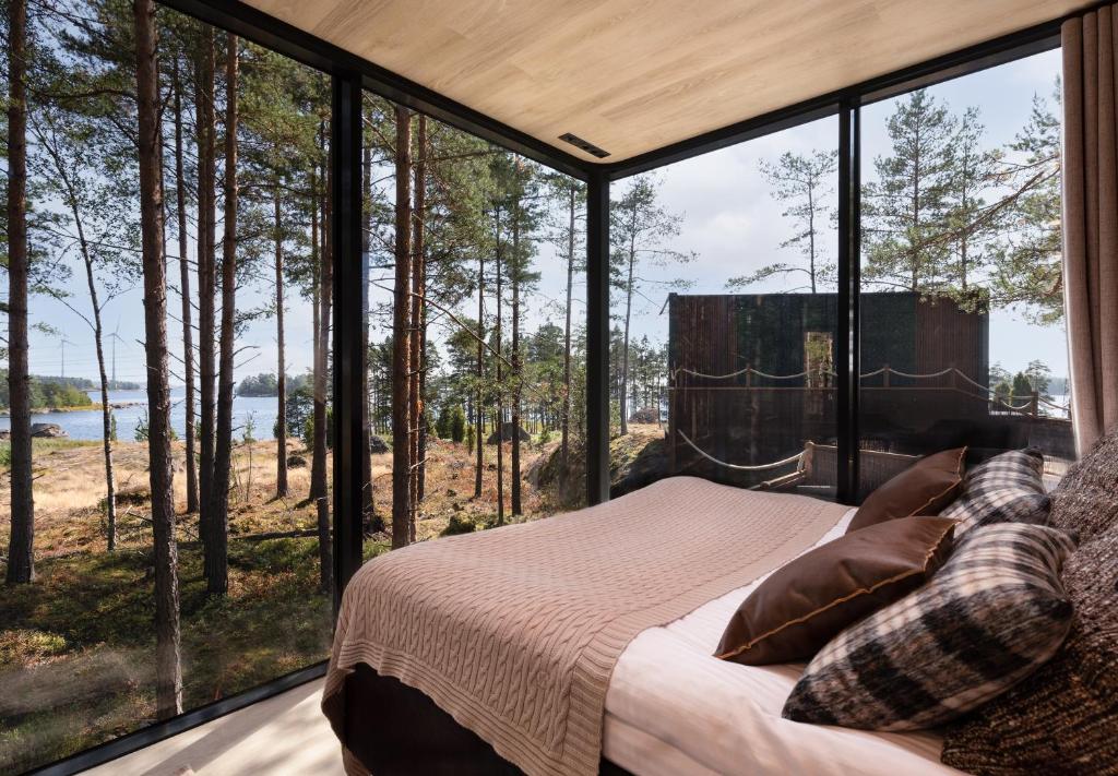 a bedroom with a bed and large glass windows at Santalahti Resort Cottages & Villas in Kotka