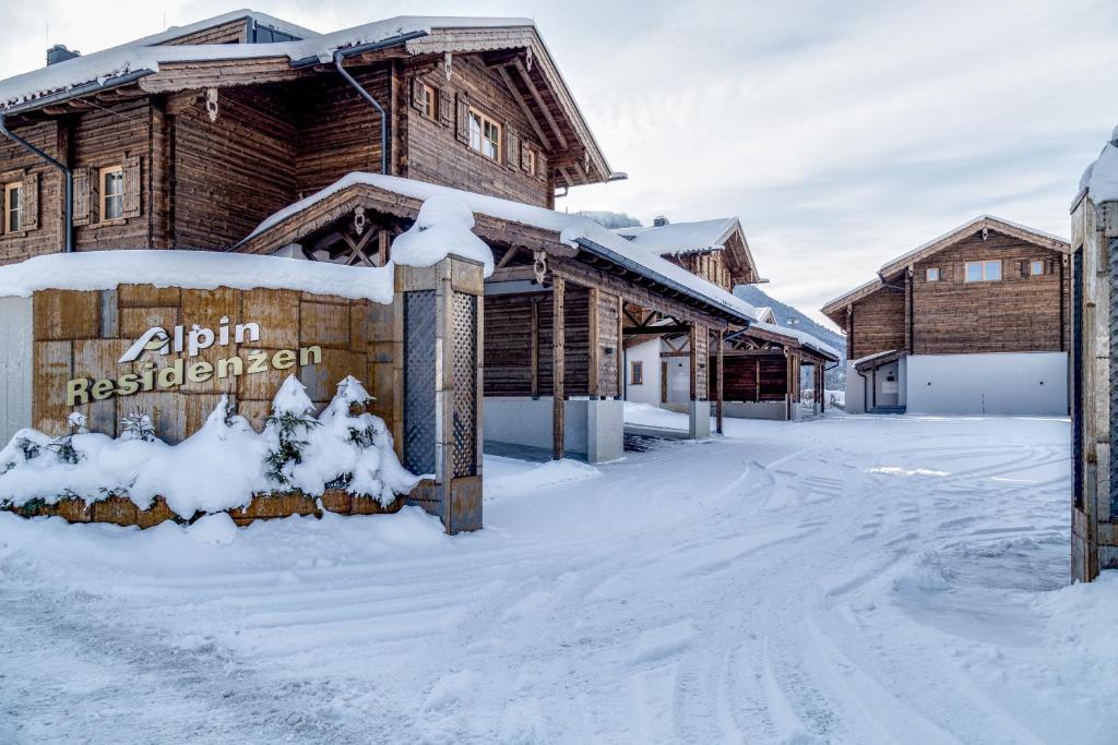 um sinal na neve em frente a uma cabana de madeira em Alpin Residenzen Panoramabahn by Alpina-Holiday em Hollersbach im Pinzgau