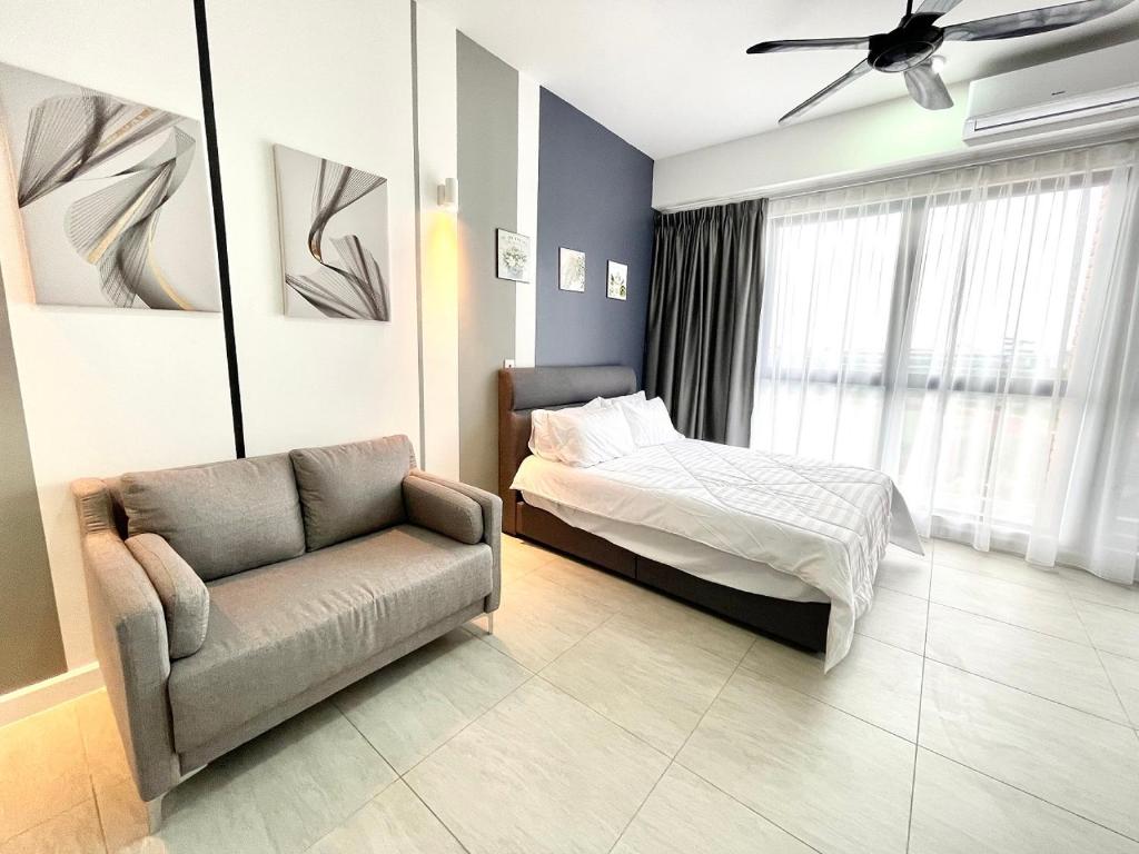 a bedroom with a bed and a couch and a chair at Bell Suites @ Sepang by Moka in Sepang