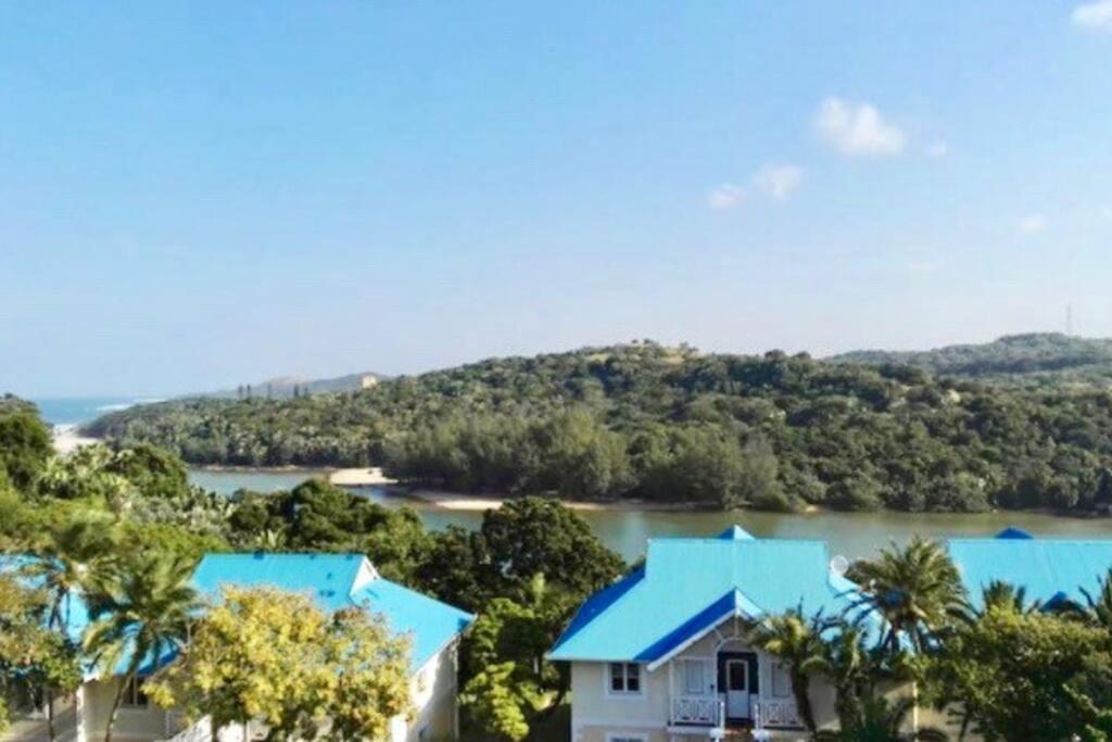 una casa con techo azul junto a un río en Caribbean Estates Montego Bay 38, en Port Edward