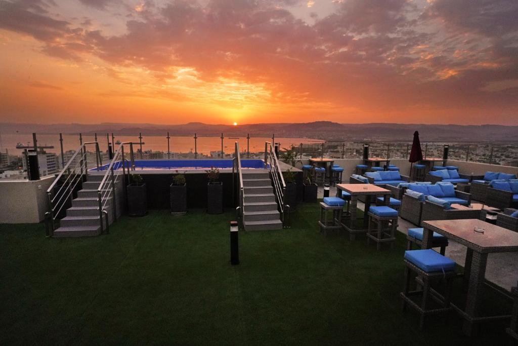 a rooftop bar with tables and chairs at sunset at Baity Boutique Hotel in Aqaba