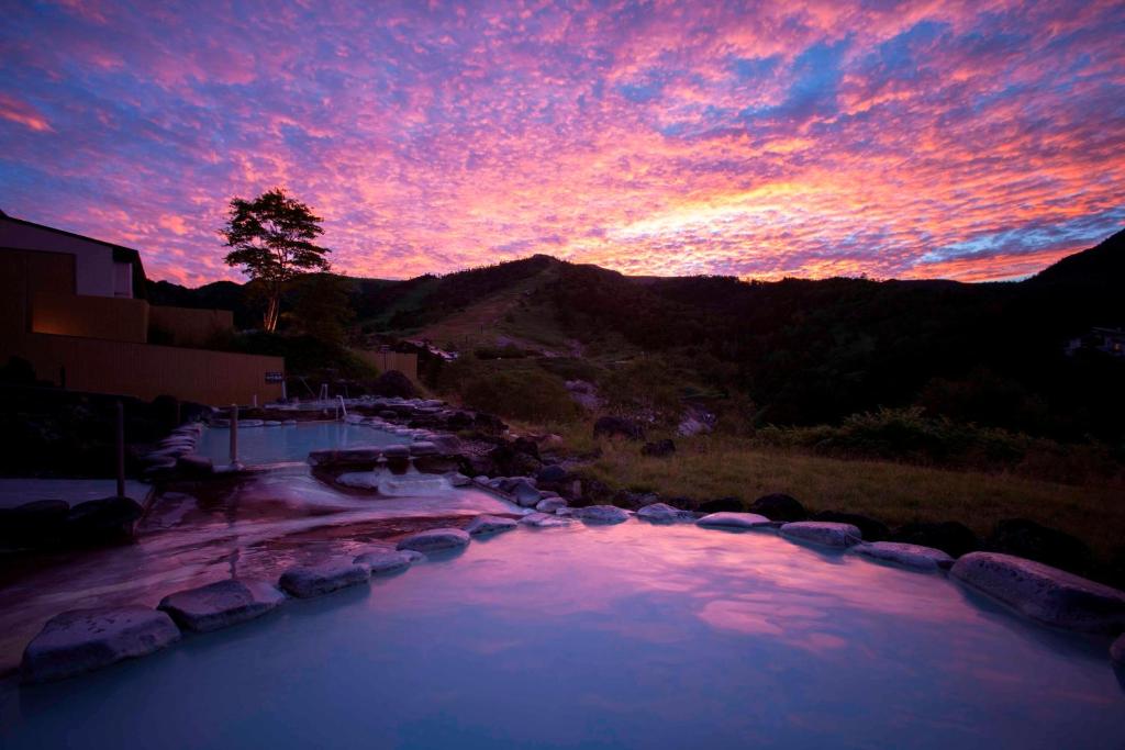 a sunset over a swimming pool at a resort at Manza Prince Hotel in Tsumagoi