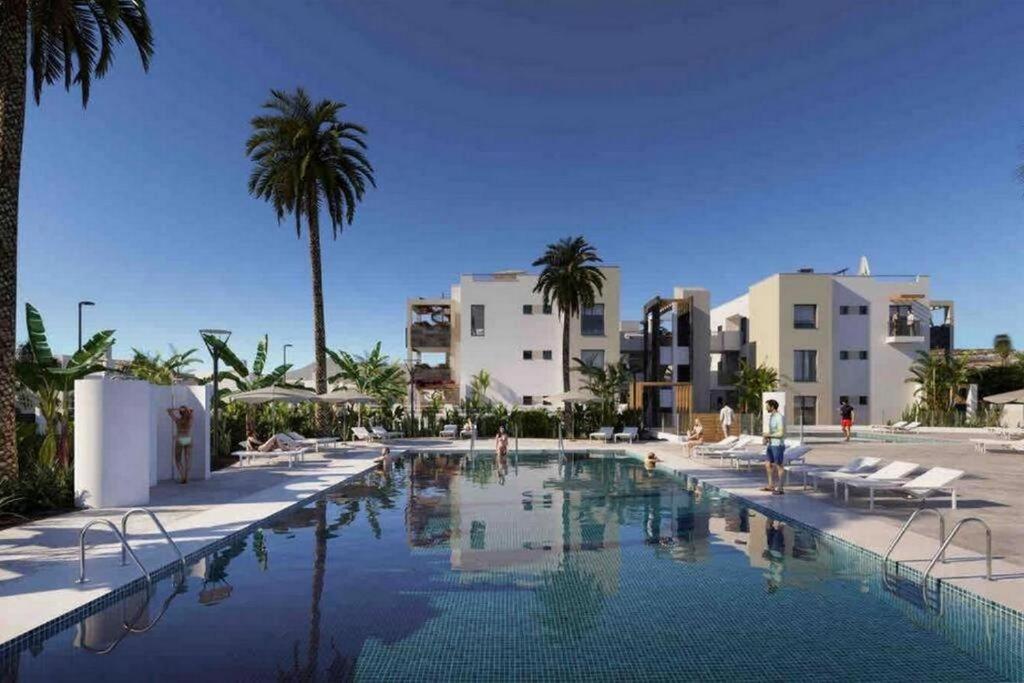 a swimming pool in a resort with palm trees and buildings at Green View Luxury appartment in new complex Pueblo Majorero next to golf course 5 min walk from the Beach and Atlantico Shopping Centre in Caleta de Fuste Next to Cassino and Elba Sara Hotel 2 bedrooms 2 bathrooms huge terace! in Caleta De Fuste