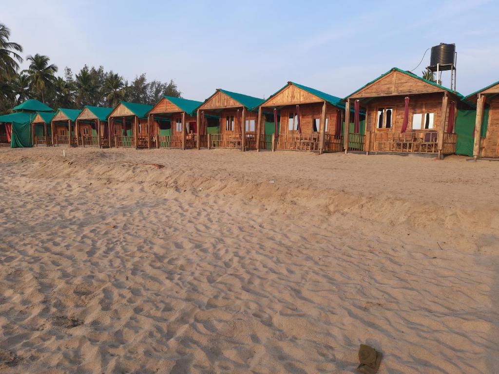a row of houses on a sandy beach at Saxony Beach Huts in Agonda