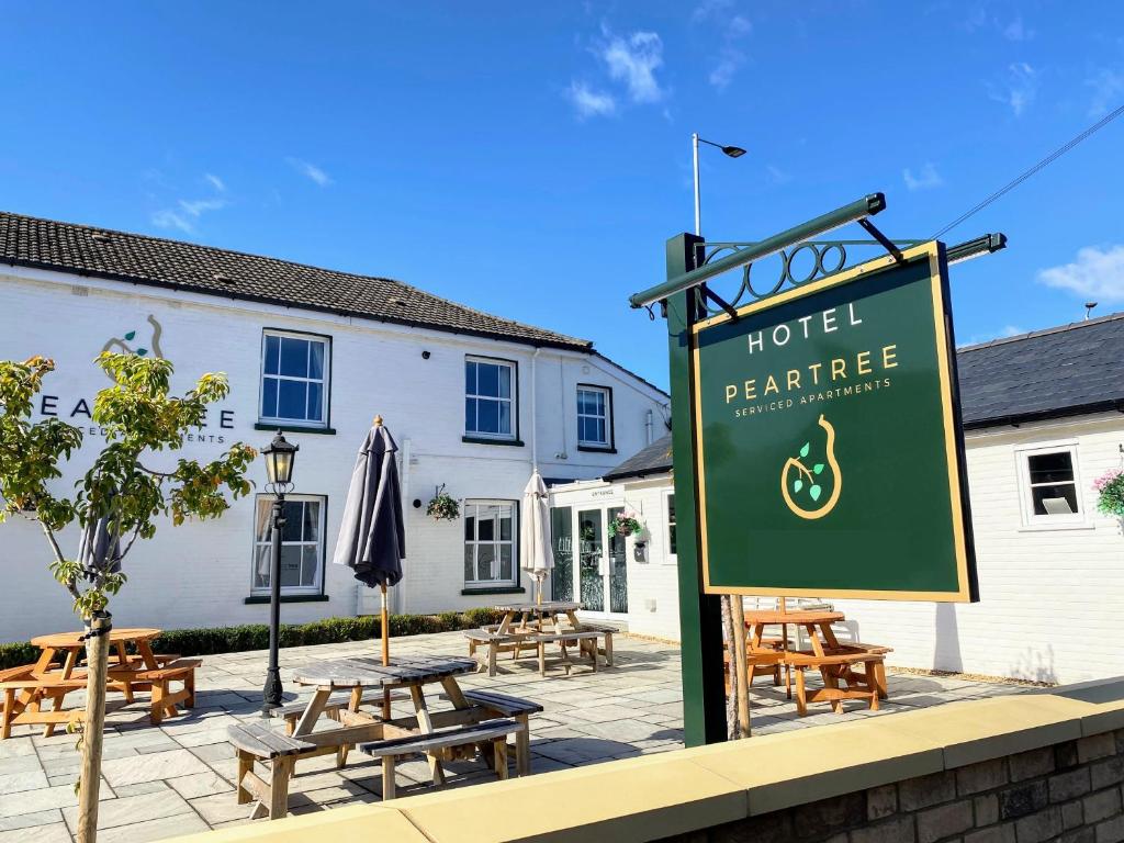 a sign in front of a hotel with tables and benches at Peartree Serviced Apartments in Salisbury