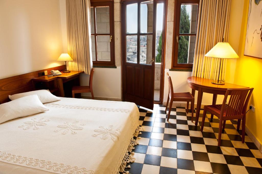 a bedroom with a bed and a checkerboard floor at Austrian Pilgrim Hospice in Jerusalem