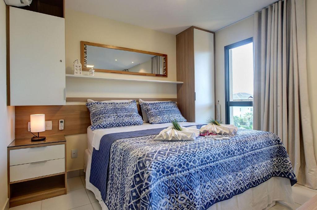 a bedroom with a blue and white bed with a window at VG Sun #406 - Quádruplo em Cumbuco por Carpediem in Caucaia
