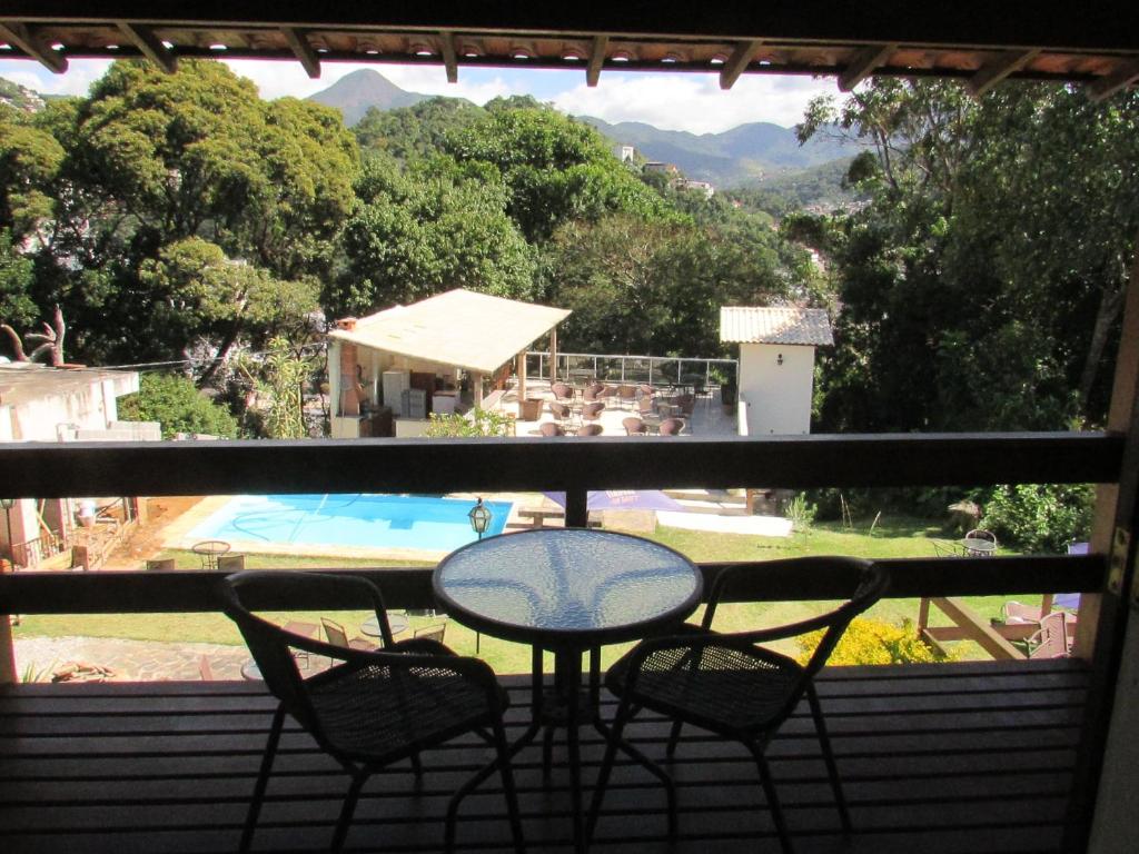 a balcony with a table and two chairs and a pool at Pousada Village Tere in Teresópolis