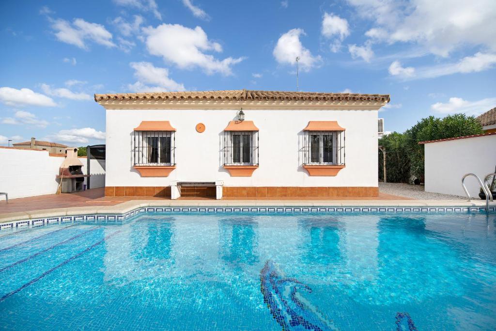 uma villa com piscina em frente a uma casa em Casa Caramelo em Chiclana de la Frontera