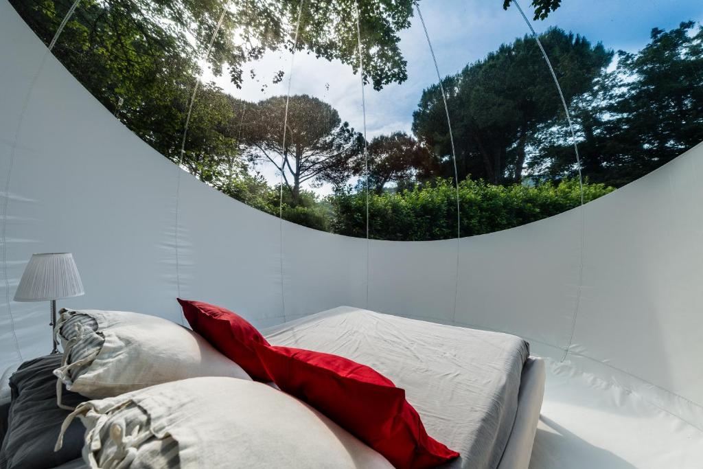 una camera con letto con cuscini rossi e specchio di Bubble Room Under The Tuscan Stars Bubble a Vicopisano