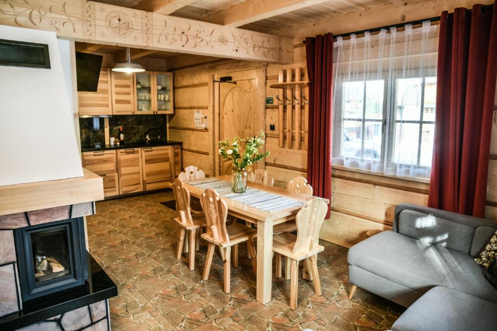 une salle à manger avec une table, des chaises et une cheminée dans l'établissement Domki 4 Seasons Zakopane, à Zakopane