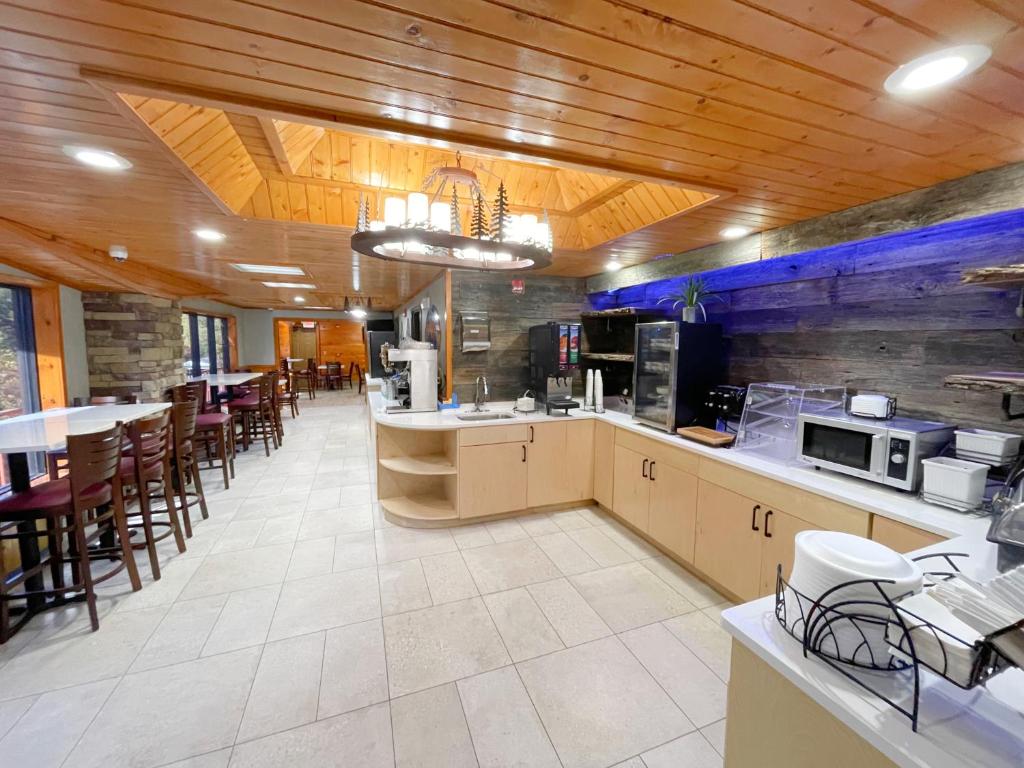 a large kitchen with wooden ceilings and tables and chairs at Baymont by Wyndham Gatlinburg On The River in Gatlinburg