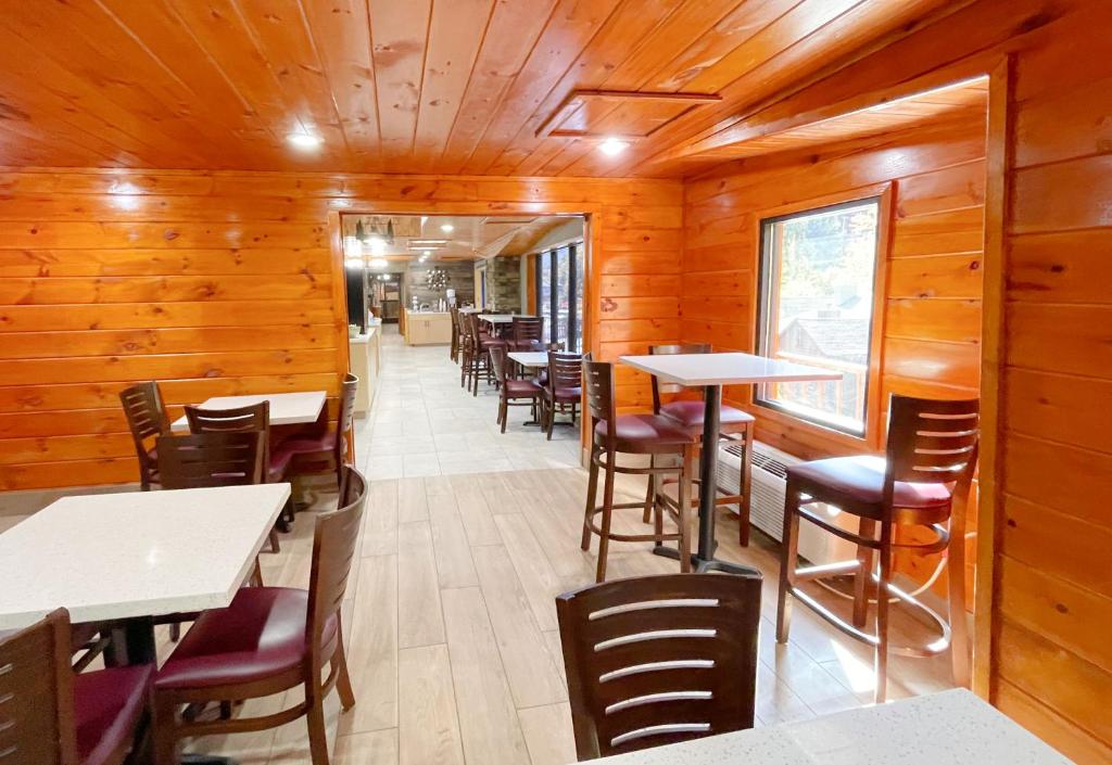 a restaurant with wooden walls and tables and chairs at Baymont by Wyndham Gatlinburg On The River in Gatlinburg