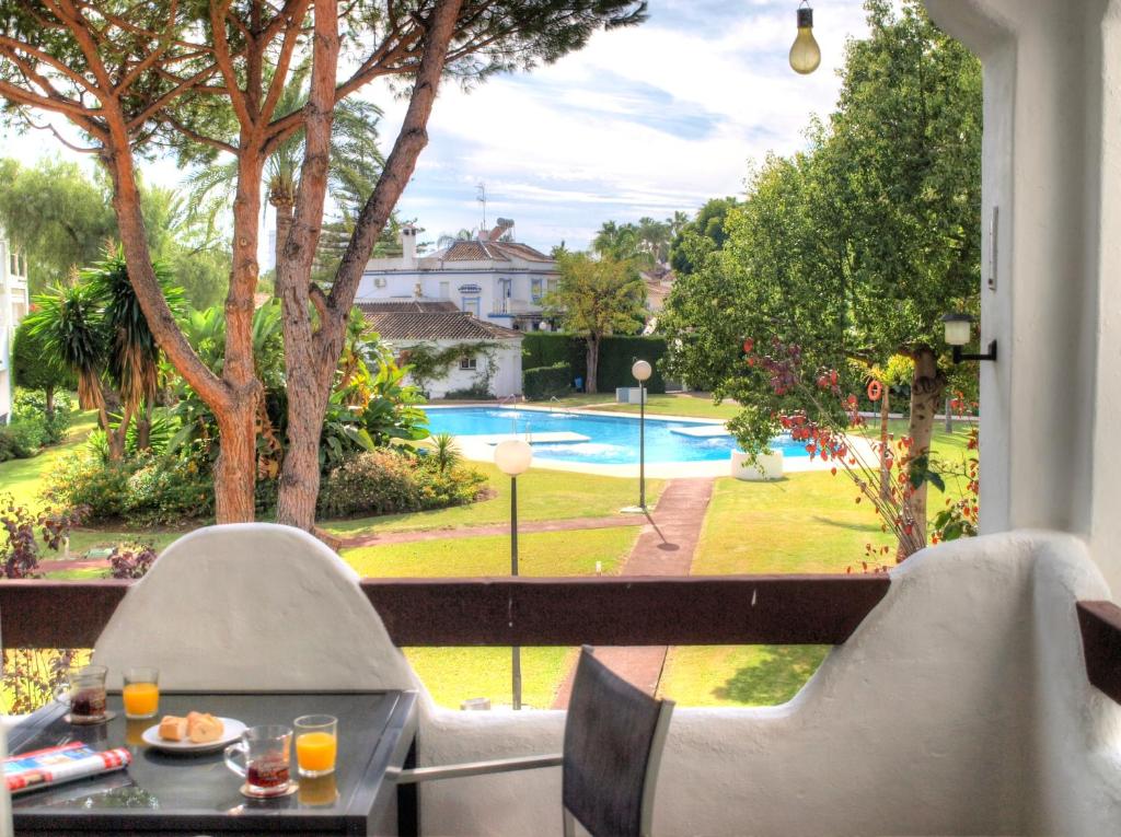 een patio met een tafel en stoelen en uitzicht op een zwembad bij Sun Beach Apartment in Estepona