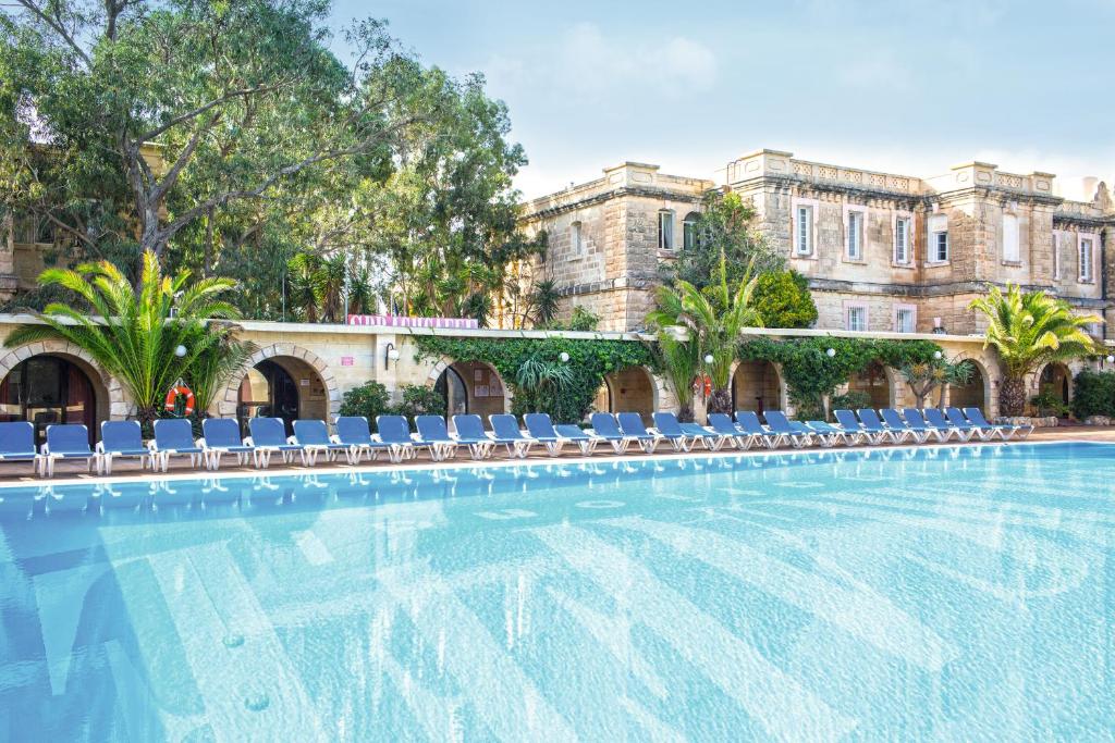 a swimming pool with chairs and a building at SC Club Village in Pembroke