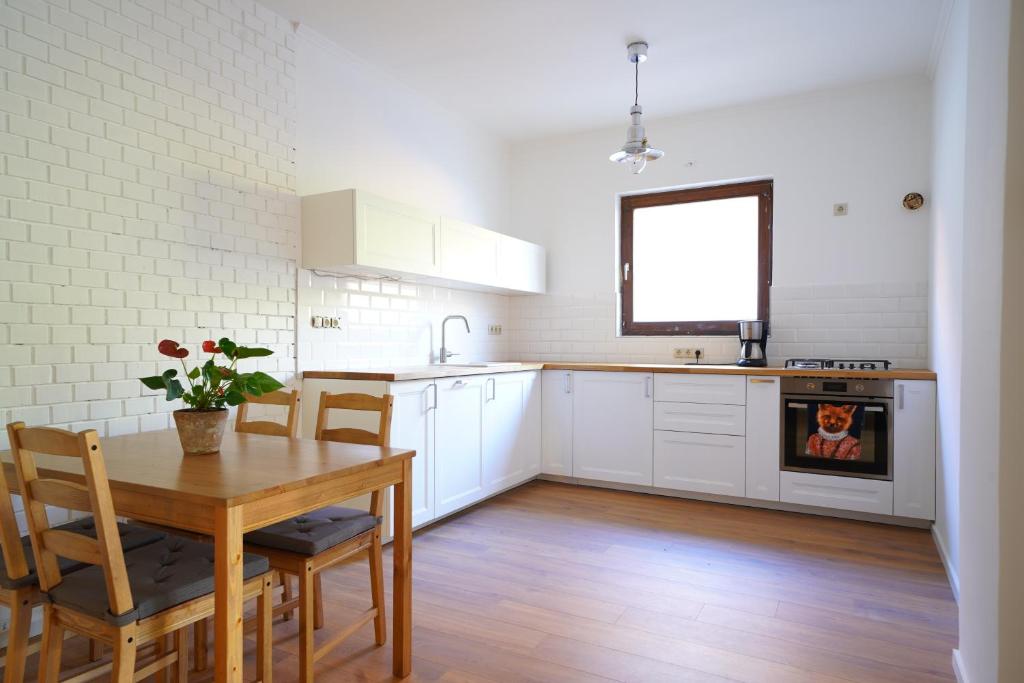 uma cozinha com armários brancos e uma mesa com cadeiras em Buda Side em Budakeszi