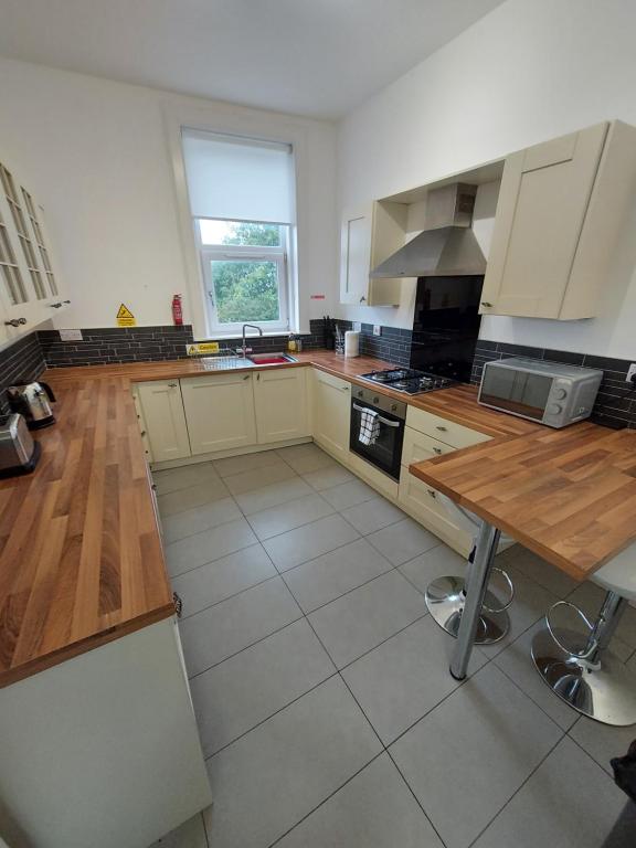 uma grande cozinha com armários brancos e uma mesa de madeira em Maze Serviced Apartment em Ayr