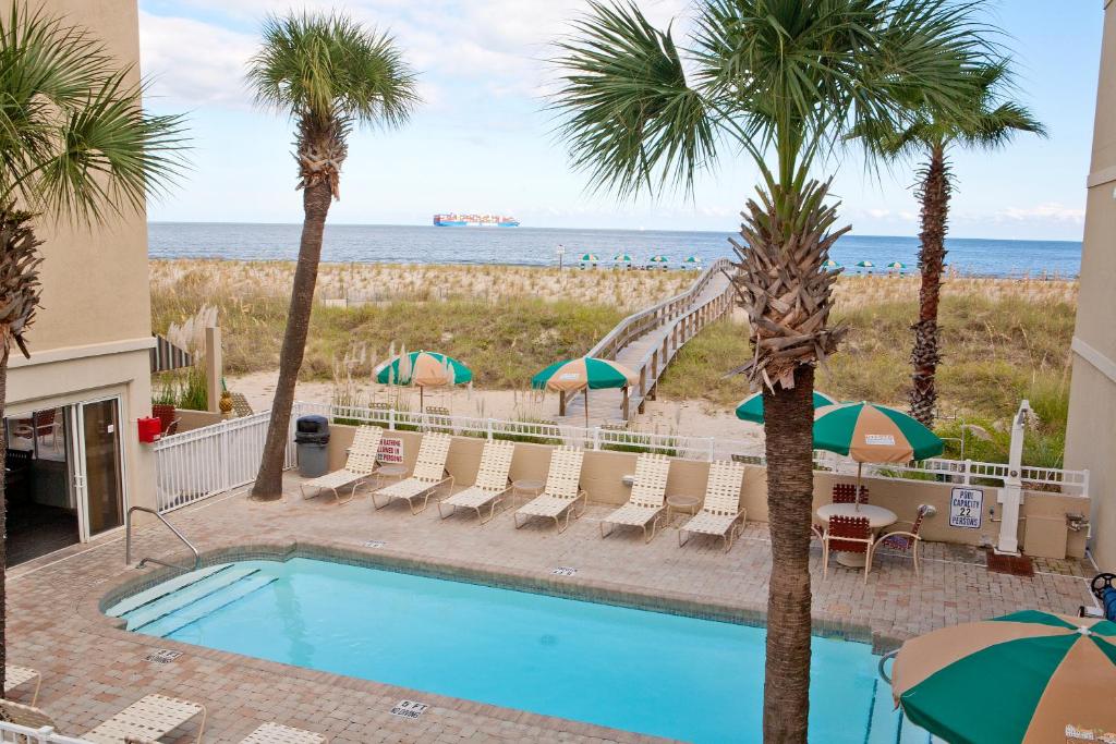 einen Pool mit Palmen und Rutsche in der Unterkunft DeSoto Beach Hotel in Tybee Island