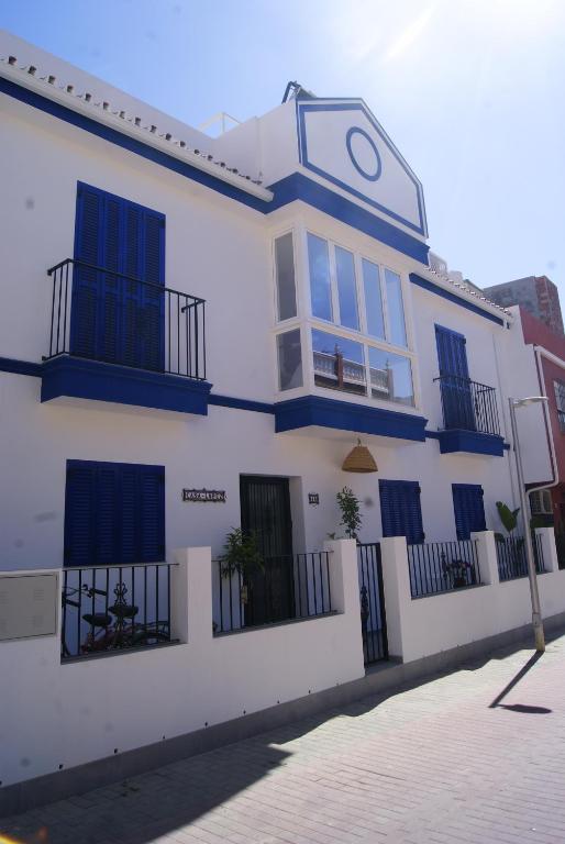 een wit gebouw met blauwe ramen en een klok erop bij Casa López- Lujosa casa de playa en Málaga in Málaga