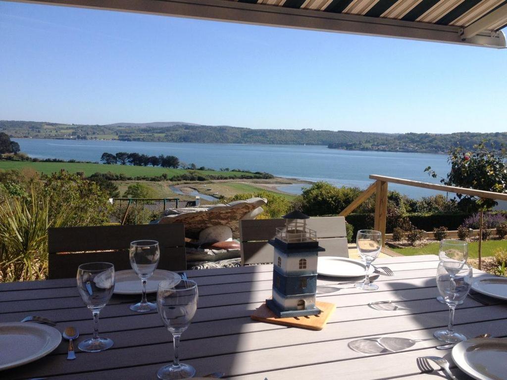 a table with wine glasses and a view of the water at Menhir in Hôpital-Camfrout