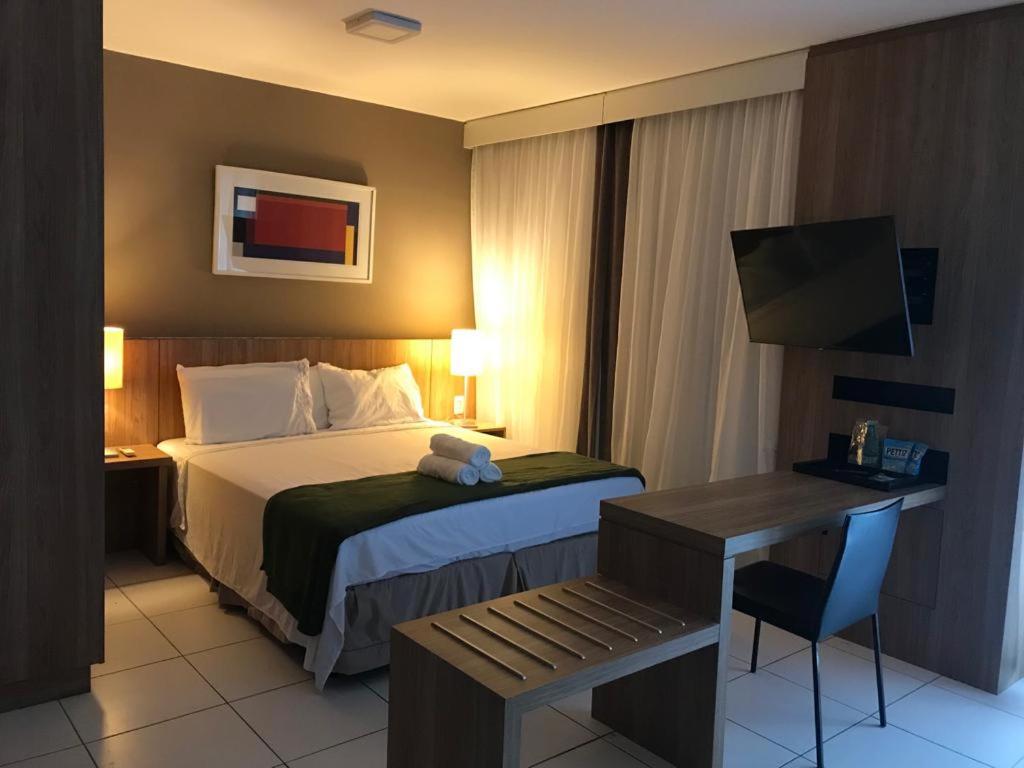 Cette chambre comprend un lit et un bureau avec une chaise. dans l'établissement RIOSTAY Riocentro Apart-Hotel, à Rio de Janeiro