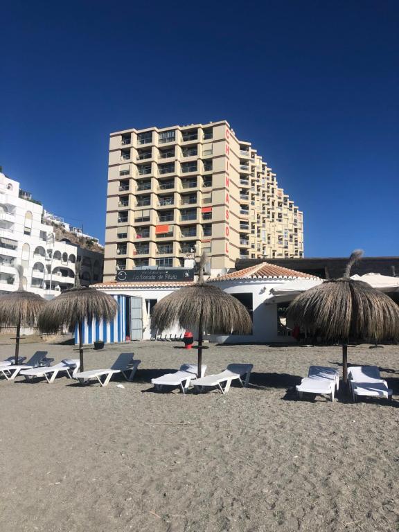 un grupo de sillas y sombrillas en una playa en Estudio Luxury Primera Linea de Playa Almuñecar Parking Gratuito, en Almuñécar