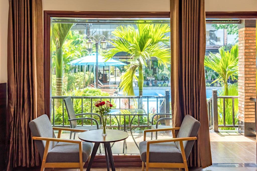 a room with a table and chairs and a balcony at Qualia Resort Phu Quoc in Phú Quốc