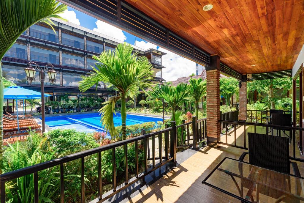 an outdoor balcony with a pool and palm trees at Qualia Resort Phu Quoc in Phú Quốc