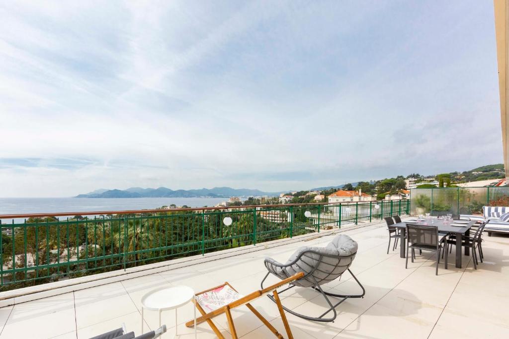 Un balcón con mesas y sillas y vistas al océano. en Luxury penthouse breathtaking sea view 200m2 terrace in the Cannes center, en Cannes