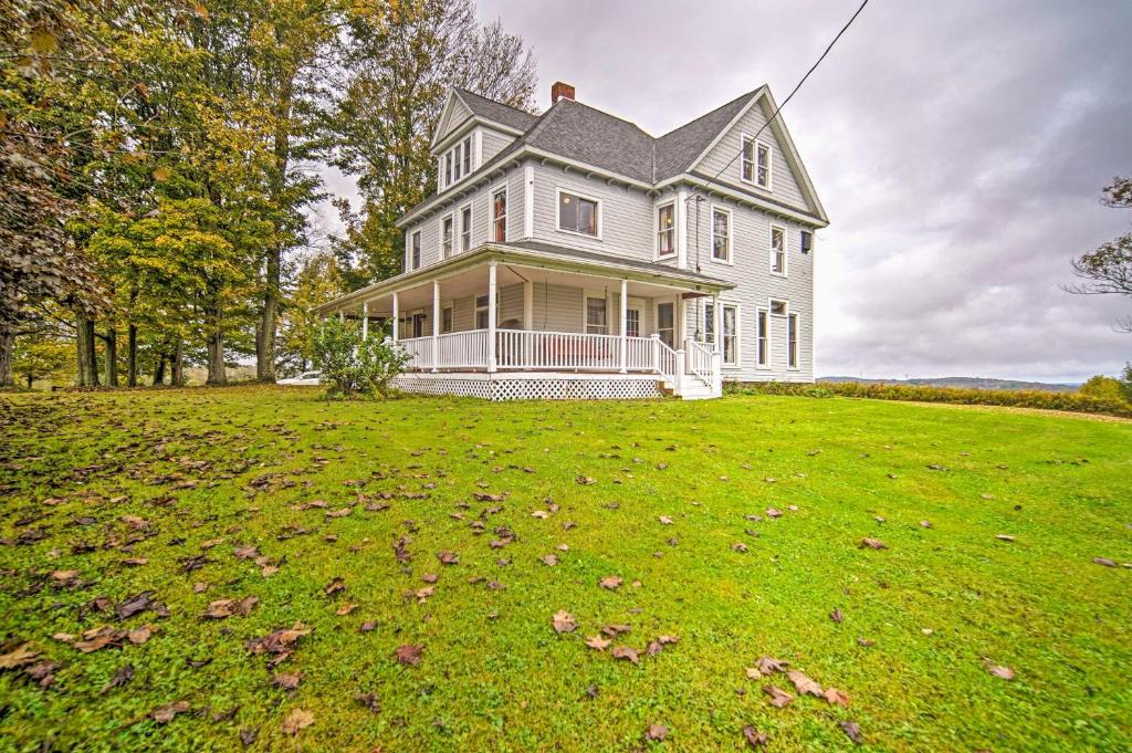 uma grande casa branca num campo relvado em Historic Victorian Farmhouse with Porch and Views! em Mayville