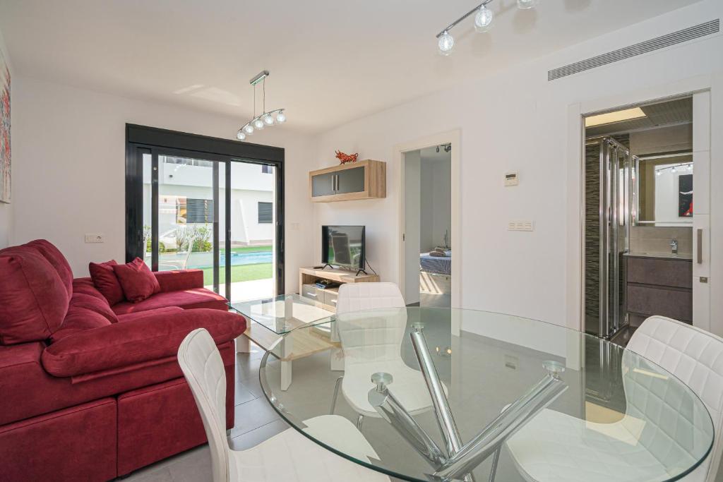 sala de estar con mesa de cristal y sofá rojo en Flamingo Playa 7, en San Pedro del Pinatar