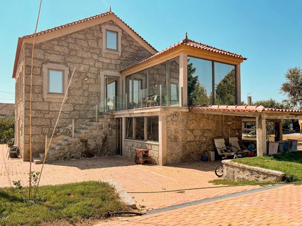 a stone house with a large glass window at DIGNUS HOUSE in Folhadosa