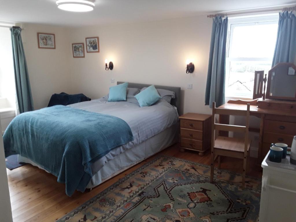 a bedroom with a bed and a desk and a window at Sharlands Farm Bed and Breakfast in Bude