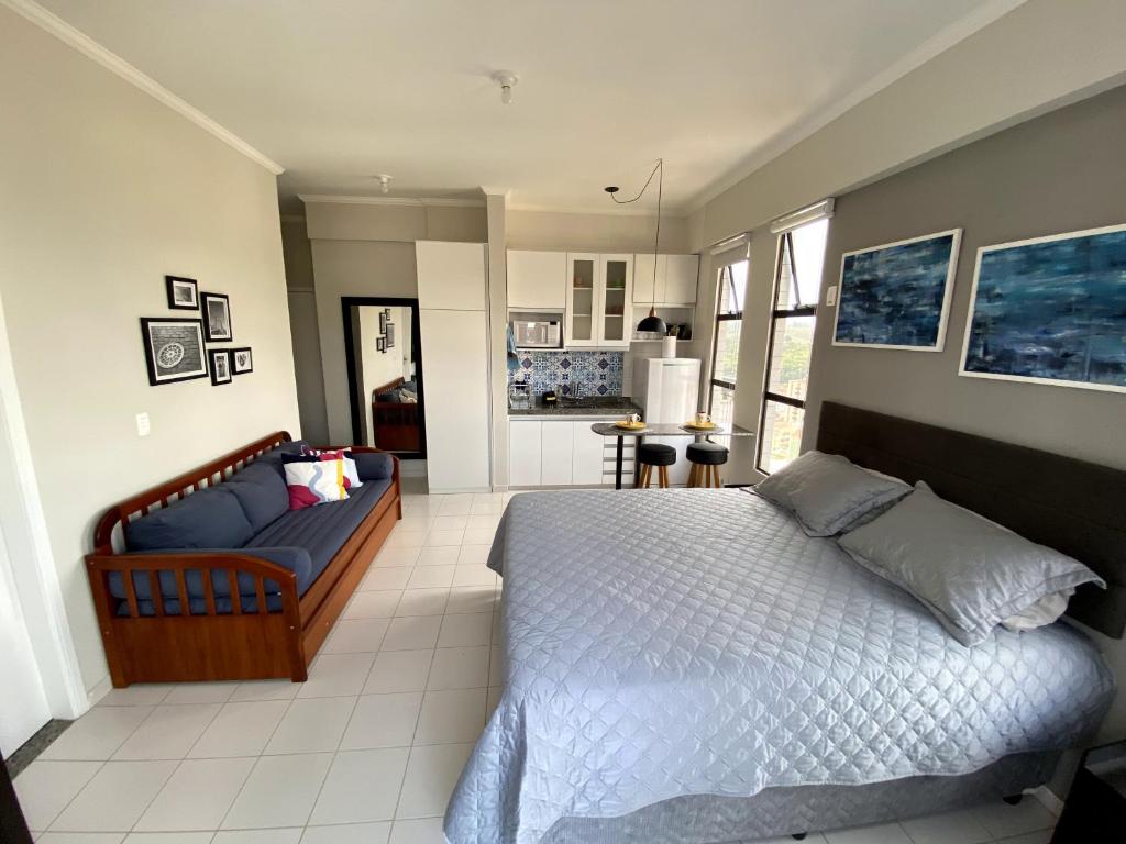 ein Schlafzimmer mit einem Bett und einem Sofa darin in der Unterkunft Apartamento Studio - Novíssimo e Aconchegante em Caxambu MG in Caxambu