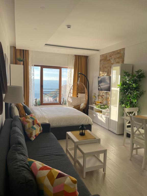 Una sala de estar con un sofá, una cama y una mesa. en Apartmani Madera, en Kopaonik
