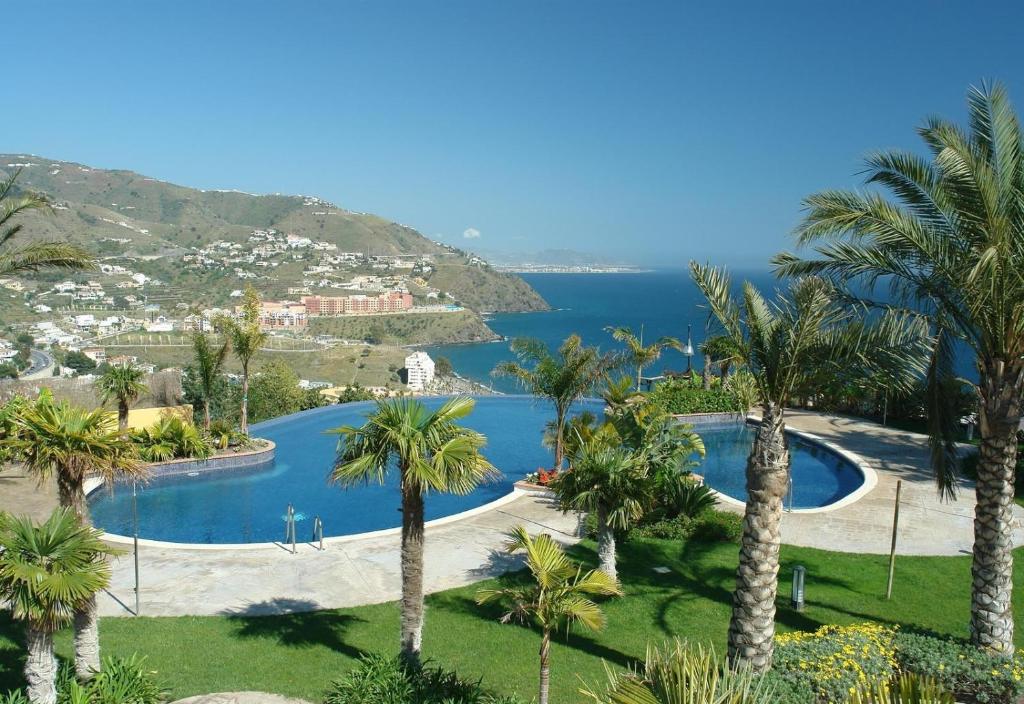 vistas a una piscina con palmeras y al océano en Villa Fuentes, en Almuñécar