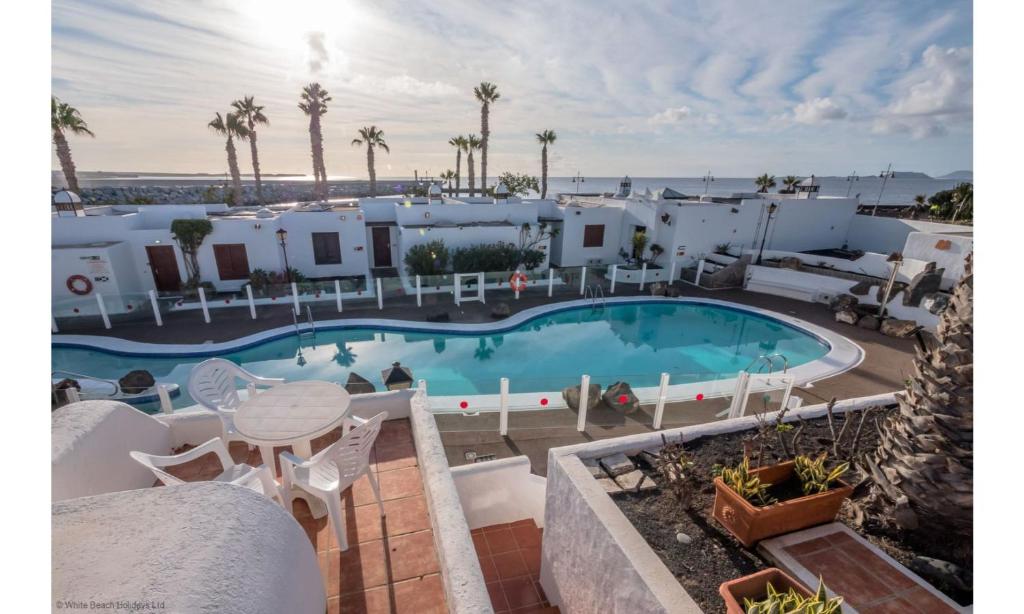 een uitzicht op het zwembad in een resort met een tafel en stoelen bij Puerto Chico 7 in Playa Blanca