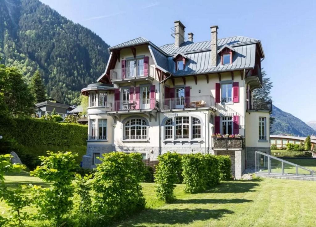 een groot huis in de bergen met struiken bij La Grande Savoyarde in Chamonix-Mont-Blanc
