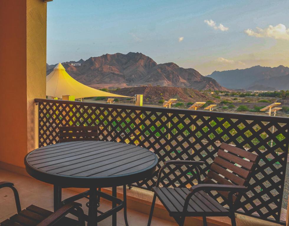 uma mesa e cadeiras numa varanda com vista para as montanhas em Hatta Guest House em Hatta