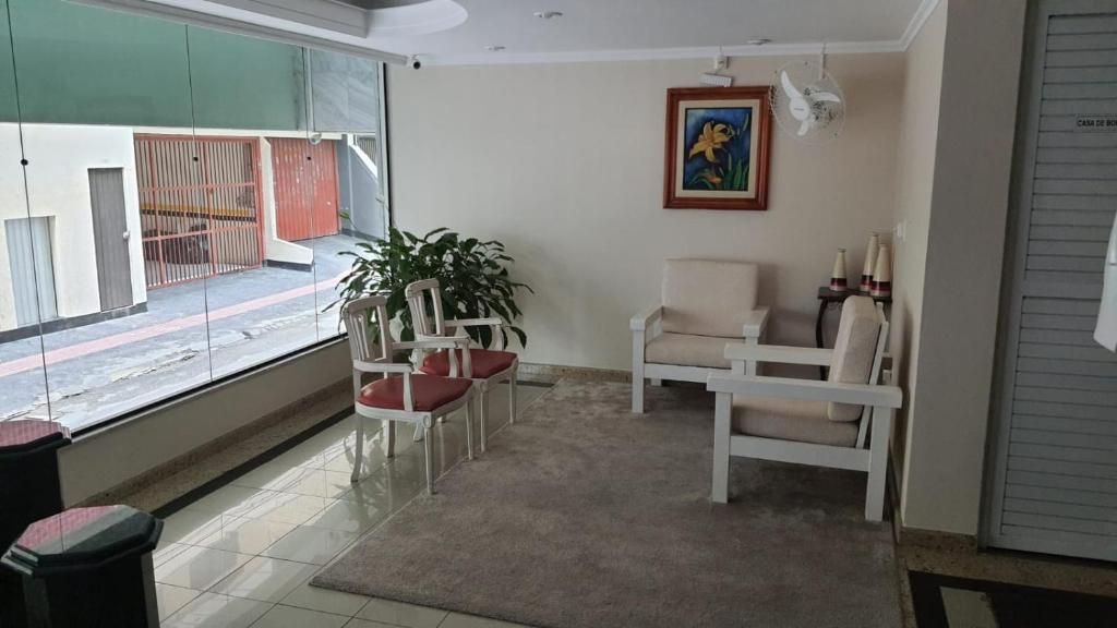 - un salon avec des chaises, une table et une fenêtre dans l'établissement Apto 1 quarto em BC, vista mar, ar condicionado split no quarto e na sala, à Balneário Camboriú