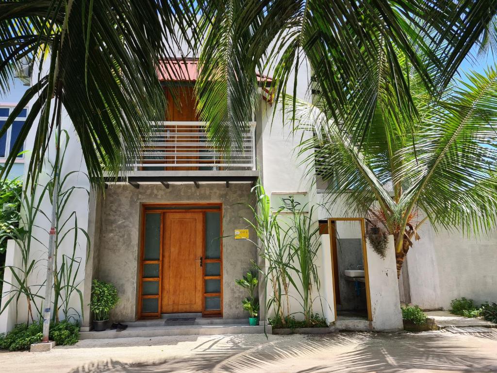 ein Haus mit einer Holztür und Palmen in der Unterkunft Dhooni Finolhu Guesthouse in Maalhos