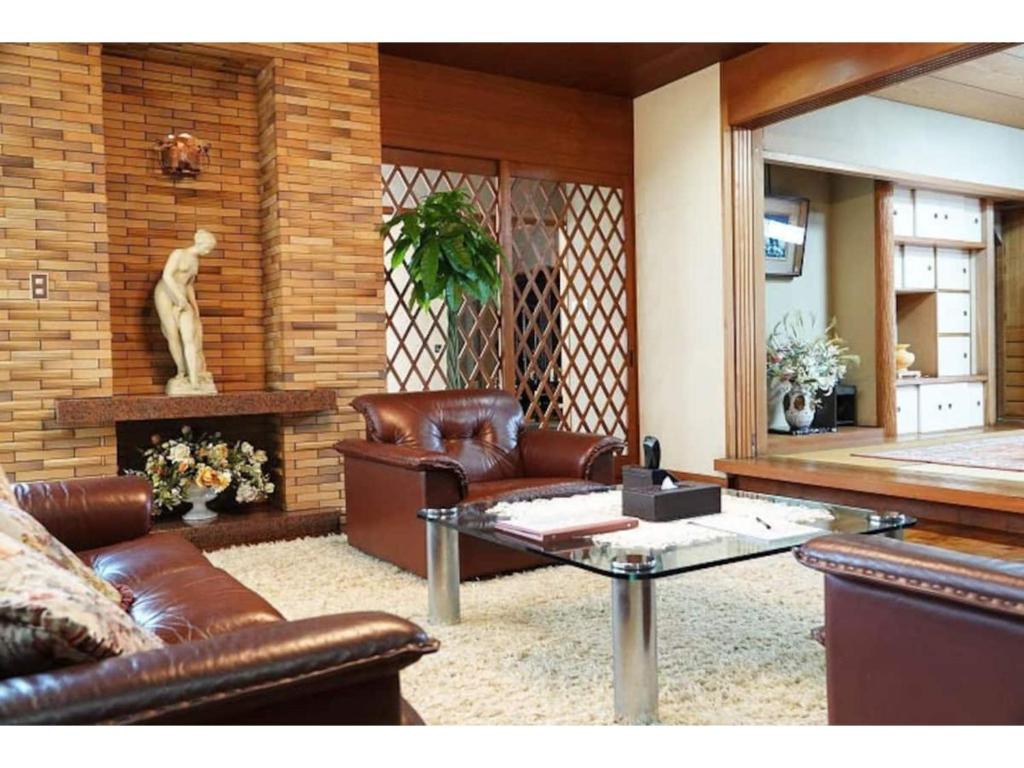 ein Wohnzimmer mit Ledersofas und einem Tisch in der Unterkunft THE TORII - Vacation STAY 68438v in Kumamoto