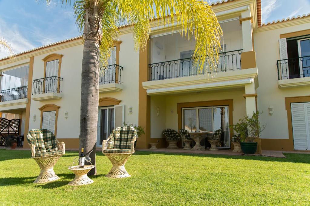 een groot huis met een palmboom in de tuin bij Carvoeiro, 2BR Pestana Gramacho Golf Apartment in Estômbar